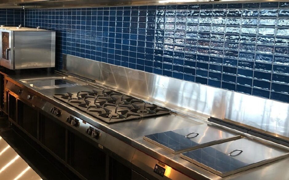 Commercial kitchen with blue teal metro tiles and stainless steel fittings